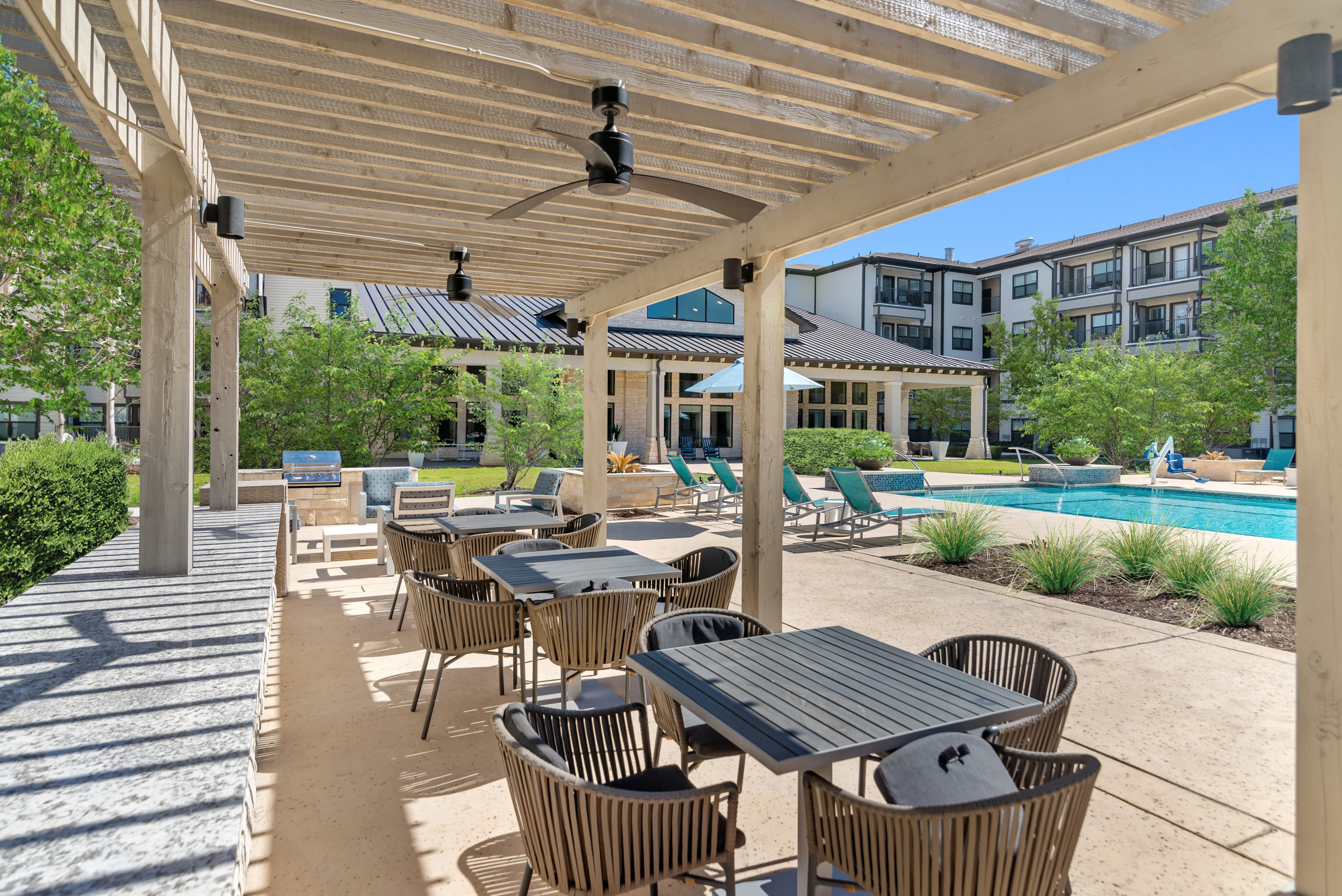 A patio with a table and chairs is covered by a wooden roof.